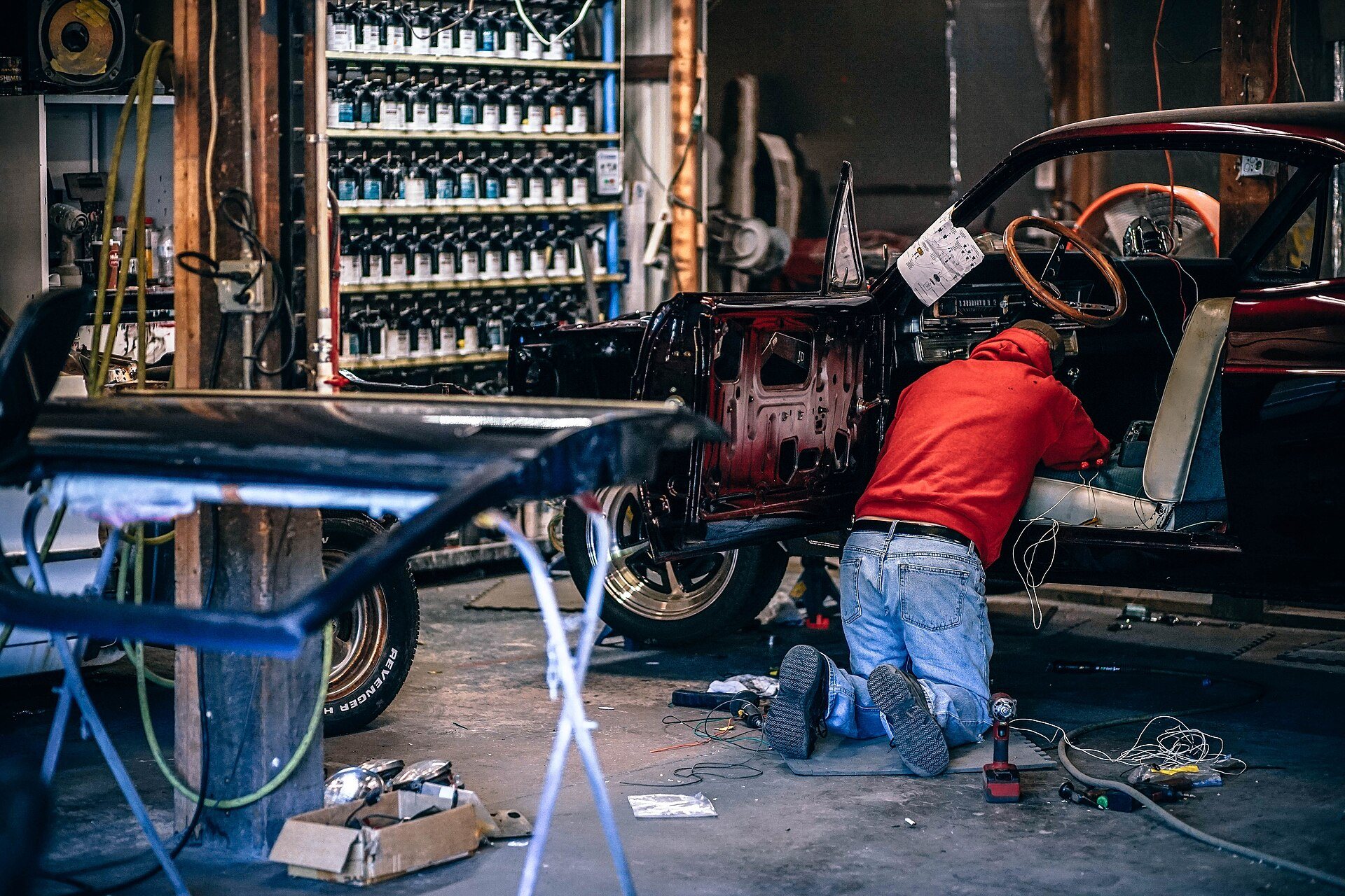 Mechanic working on a classic car inside a restoration workshop.